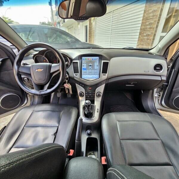 Vista frontal del interior del Chevrolet Cruze LS 2012 con volante Chevrolet y pantalla táctil en el tablero.